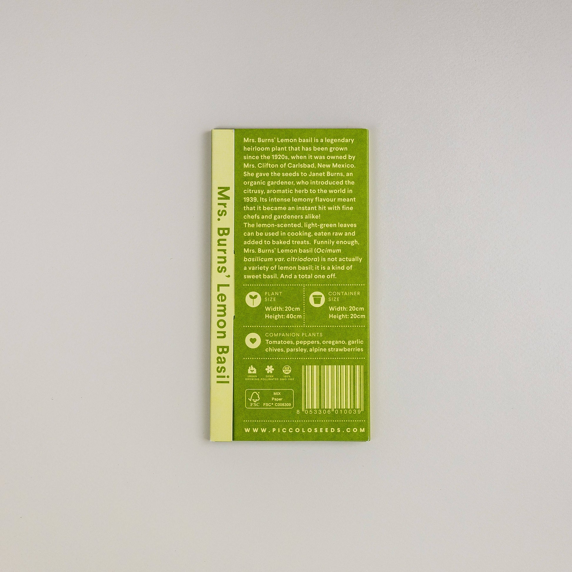 Eine grüne Piccolo Seeds-Packung mit der Aufschrift "Basilikum Mrs. Burns Zitrone" steht aufrecht auf einer hellen Fläche und zeigt Pflanzanweisungen, Symbole und eine Beschreibung dieses aromatischen Krauts und der geschätzten Erbstückpflanze.
