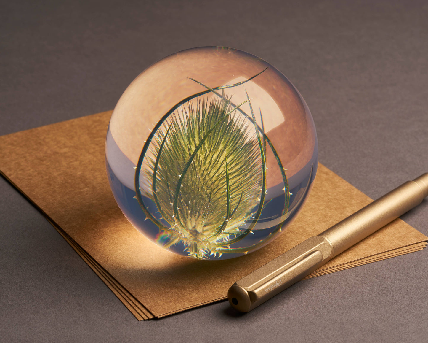 Der Hafod Grange | Briefbeschwerer mit Karde von Hafod Grange liegt auf braunen Umschlägen neben einem goldenen Stift - stilvolle Schreibtischdeko auf neutraler Oberfläche.
