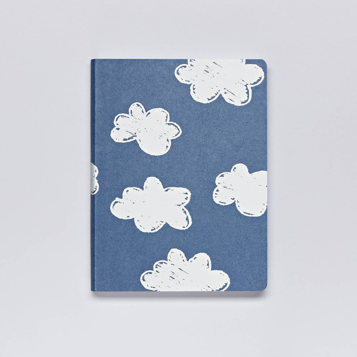 Ein Notizbuch von nuuna | „Head In The Clouds“ Graphic L A5+ von nuuna mit handgezeichneten weißen Wolkenillustrationen auf einem blauen Einband aus recyceltem Denim und Premium-Papier, der auf einem schlichten weißen Hintergrund prangt.