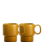 Zwei senfgelbe Sagaform GmbH Kaffeebecher Gelb (2-teilig) mit strukturiertem oberen Rand stehen nebeneinander und heben das skandinavische Design auf weißem Hintergrund hervor.