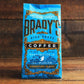 Eine blaue Tüte Brady's Coffee Company | 227 g gemahlener Signature Blend Kaffee mit goldenen und schwarzen Verzierungen und der Aufschrift "handcrafted high-grade Irish Roast from Co. Wicklow, steht auf einer Holzunterlage.