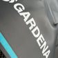 Nahaufnahme des grauen Gardena Textilschlauchs Liano™ Xtreme 1/2" Balkon und Terrasse mit weißem Branding und blauem Randstreifen; seine Oberfläche wirkt leicht faltig.