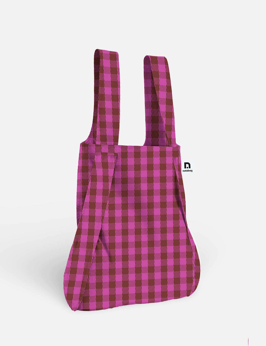 Die Notabag | Wandelbare Tasche und Rucksack „Kirsche“ von Notabag steht aufrecht vor einem schlichten weißen Hintergrund und präsentiert ihr rosa-burgunderrotes Karomuster. Diese innovative Tasche lässt sich mühelos von einer Tragetasche in einen Rucksack verwandeln – eine wahrhaft wandelbare Tasche für den Alltag.