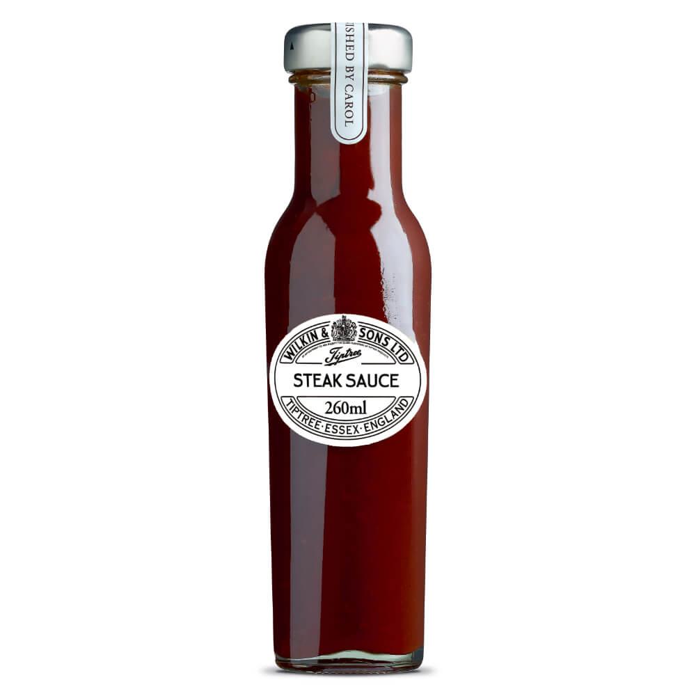 Eine klare Glasflasche „Wilkin & Sons | Tiptree Steak Sauce Rauchig würzig“ (260 ml) verfügt über einen silbernen Verschluss und ein ovales weißes Etikett auf der Vorderseite, auf dem der Produktname und die Füllmenge angegeben sind. Diese klassische englische Würzsauce von Wilkin & Sons überzeugt durch einen rauchigen und würzigen Geschmack und eignet sich perfekt, um Ihre Lieblingsgerichte zu verfeinern.