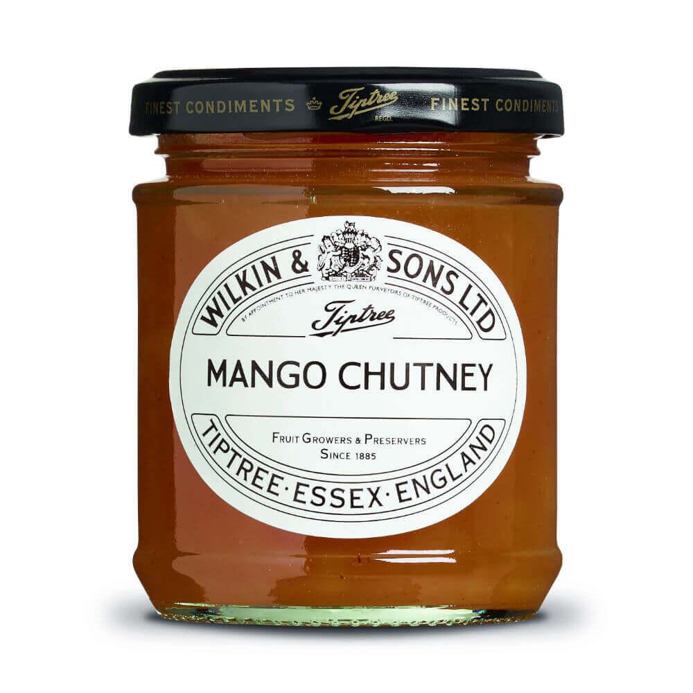 Ein 220-g-Glas mit „Wilkin & Sons Tiptree Chutney Mango“, mit einem weißen Etikett mit schwarzer Schrift und einem goldenen Deckel. Im Glas hat das Chutney eine goldorange Farbe.