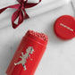Die Solstickan Design | Streichholzdose Rot ist ein roter zylindrischer Streichholzhalter von Solstickan Design, mit dem metallischen Solsticke Boy, gefüllt mit extra langen Streichhölzern. Dazu gibt es einen passenden Deckel und eine weiße Kerze mit Schleife auf Marmor.