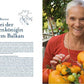 Eine ältere Frau mit grauen Haaren in einem roten Hemd lächelt und hält einen Korb mit bunten Tomaten in der Hand. Links steht ein deutscher Text über Trudi Borsos mit dem Titel "Tomatenlust | Die Geheimnisse der Tomatenpioniere" vom Haupt Verlag.