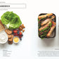 Draufsicht auf die Zutaten für ein BLT-Sandwich - Brot, Salat, Tomate, Speck, Zwiebel - ideal für die Super-Lunchbox des DK Verlags: Über 80 abwechslungsreiche Meal-Prep-Rezepte für Genießer. Rechts: fertige Sandwiches mit Obst, Keksen und Joghurt als Lunchbox-Ideen.