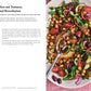 Ein bunter Salat mit Kichererbsen, Tomaten, Grünzeug, roten Zwiebeln und Radieschen wird auf einem rosa Teller mit einem silbernen Löffel neben dem Kochbuch "Happy | Weil diese Rezepte glücklich machen" vom DK Verlag auf weißem Hintergrund serviert.