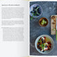 Eine Kochbuchseite aus "Vergnügt Vegan" vom Gerstenberg Verlag zeigt links ein deutsches veganes Obstsalatrezept und rechts ein Foto von Obstsalat, ganzen Früchten, Zitronenhälften und Beeren auf einem Holzbrett.