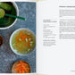 Im offenen Kochbuch "Vergnügt Vegan" vom Gerstenberg Verlag finden sich Rezepte wie Romana-Ingwer-Brühe, abgebildet mit klarer Brühe, Pak Choi, Karottenstreifen und Kräutern - perfekt für alle, die neue vegane Rezepte entdecken wollen.