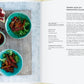 Ein aufgeschlagenes Kochbuch "Vergnügt Vegan | Rezepte und Tipps für die ganze Familie" aus dem Gerstenberg Verlag zeigt ein Rezept für Tempeh-Chips mit Granatapfelglasur, begleitet von zwei grünen Schalen mit dem Gericht, Sauce, Koriander und Granatapfelkernen auf einem weißen Tisch.