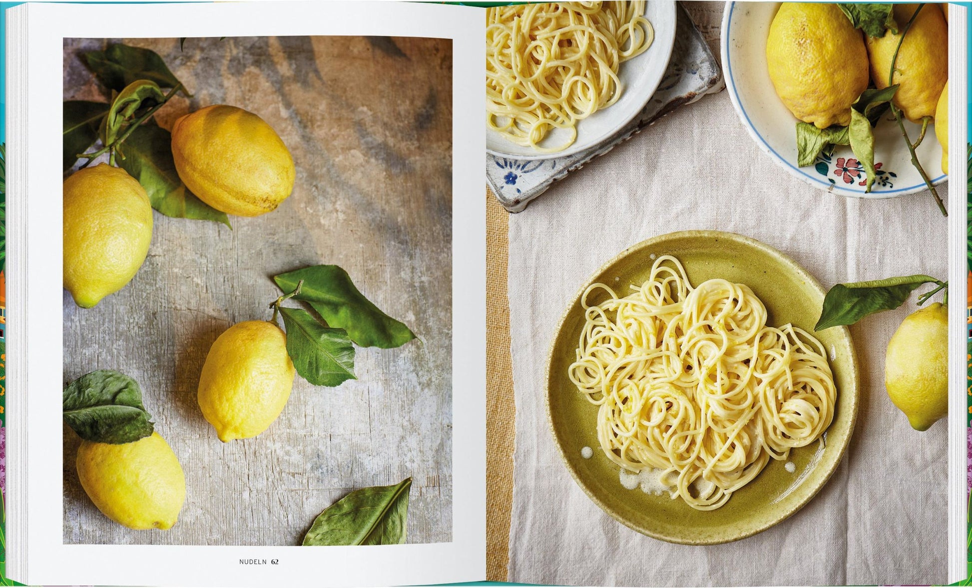 Ein aufgeschlagenes Kochbuch, "Die Küche von Amalfi | 75 authentische Rezepte" vom Gerstenberg Verlag, zeigt frische Zitronen und Teller mit Spaghetti - einige mit Zitrone - die den Glanz der italienischen Küche von der Amalfiküste einfangen.