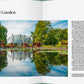 Ein aufgeschlagenes Buch aus dem Gerstenberg Verlag "Botanische Gärten | Die schönsten Pflanzenparadiese der Welt" zeigt den Missouri Botanical Garden mit einem Teich mit Skulpturen, üppigem Grün und dem gläsernen Gewächshaus, das sich im Wasser spiegelt. Der Text über den Garten ist sichtbar.