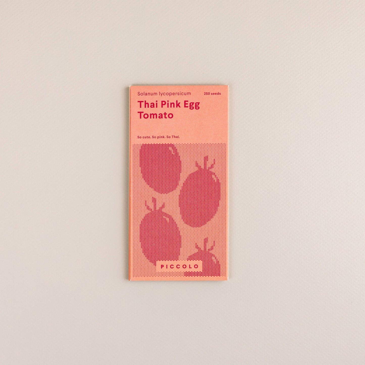Eine Packung mit der Aufschrift "Piccolo Seeds | Tomaten-Thai-rosa Ei" von Piccolo Seeds zeigt drei Tomaten und enthält 350 Samen dieser einzigartigen südostasiatischen Tomatensorte, die auf einem schlichten, gebrochen weißen Hintergrund abgebildet sind.