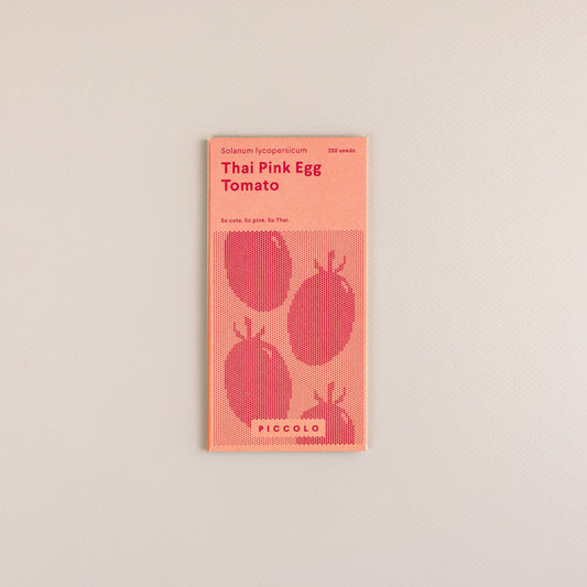 Eine Packung mit der Aufschrift "Piccolo Seeds | Tomaten-Thai-rosa Ei" von Piccolo Seeds zeigt drei Tomaten und enthält 350 Samen dieser einzigartigen südostasiatischen Tomatensorte, die auf einem schlichten, gebrochen weißen Hintergrund abgebildet sind.