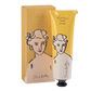 Eine gelb-weiße Tube Archivist Gallery | 'Sheabutter' Handcreme steht neben der dazugehörigen Schachtel. Beide zeigen eine minimalistische Strichzeichnung eines Frauengesichts und eines Oberkörpers.