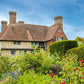 Ein charmantes englisches Cottage mit Ziegeldach erhebt sich hinter einem lebendigen Garten, festgehalten in "Gärtnern wie Gott in England" von Callwey Verlag: Detaillierte Anleitungen und inspirierende Bilder klassischer Gartengestaltung.