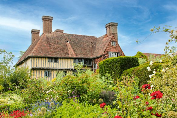 Ein charmantes englisches Cottage mit Ziegeldach erhebt sich hinter einem lebendigen Garten, festgehalten in "Gärtnern wie Gott in England" von Callwey Verlag: Detaillierte Anleitungen und inspirierende Bilder klassischer Gartengestaltung.