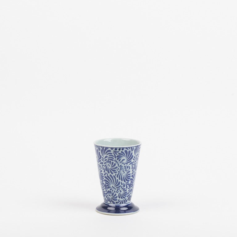 Die Des Pots Keramikvase klein in blau-weiß mit floralem Muster (H 15 cm, Ø 10 cm) präsentiert sich handgefertigt und glasiert auf schlicht weißem Hintergrund.