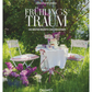 Ein kleiner Tisch mit weißem Tuch, Teetassen, Kuchen und Osterdeko steht zwischen zwei weißen Stühlen inmitten blühenden Flieders. In dem üppigen Garten liegt das Buch "Frühlingstraum | Rezepte für Frühlingsgefühle und österliche Anlässe" vom Callwey Verlag aus.