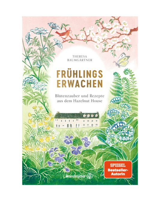 Buchumschlag von "Frühlingserwachen | Blütenzauber und Rezepte aus dem Haselnusshaus" vom Brandstätter Verlag, mit illustrierten Frühlingsblumen, Wildkräutern, Vögeln, einem kleinen Haus im Grünen, roter SPIEGEL-Bestsellerplakette. Text auf Deutsch.