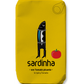 Auf einer gelben Sardinen-Dose ist eine Cartoon-Sardine abgebildet, die aufrecht in Kleidung steht und eine Tomate an der Leine hält. Der Text lautet: Sardinha | Sardine in würziger Tomate. Dieses verspielte Design von Sardinha unterstreicht die köstliche Kombination aus würzigen Tomatenaromen und den wertvollen Omega-3-Vorteilen.