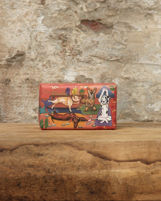 Die ESC | 'Dog' pflanzliche Handseife mit fruchtig blumigem Duft von The English Soap Company liegt in bunter rechteckiger Verpackung mit Hunde- und Knochenmotiven auf rustikalem Holz vor einer verwitterten Steinwand.