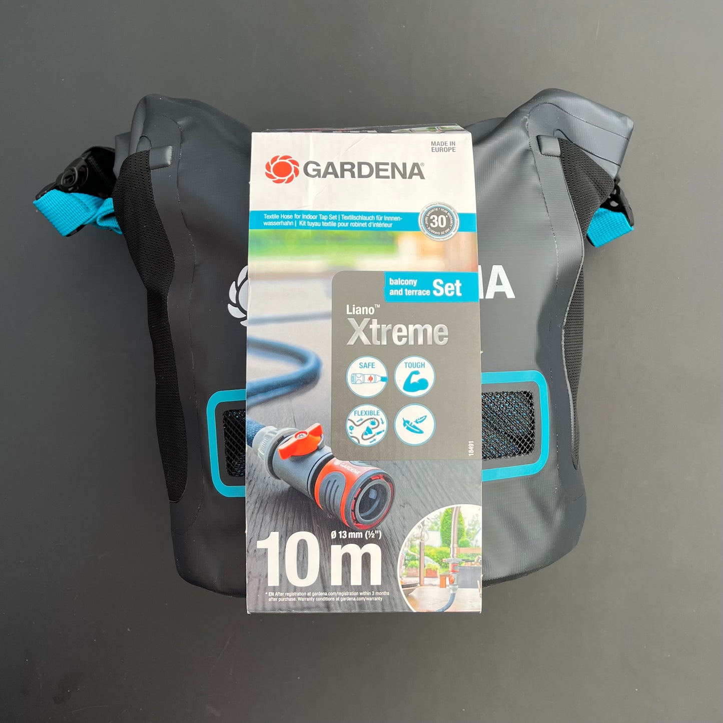 Abgebildet ist ein verpacktes Gardena Textilschlauch Liano™ Xtreme 1/2" Balkon und Terrasse Set mit Verbindern vor schwarzem Hintergrund.