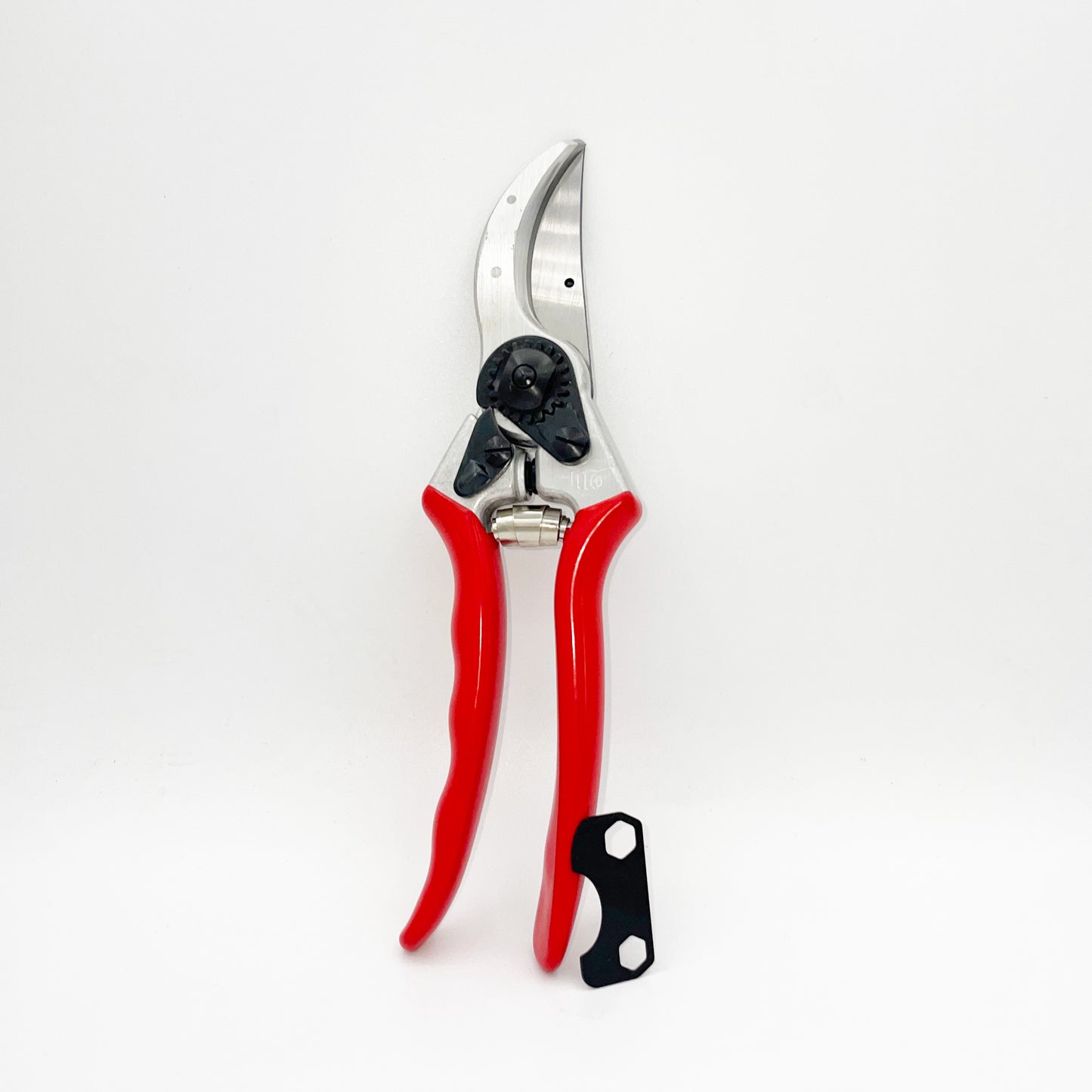 Ein Paar Felco 2 Einhand-Baum-,Reb-,Gartenschere (25mm, Größe L) mit leuchtend roten Griffen steht aufrecht auf weißem Hintergrund neben einem kleinen schwarz-weißen Einstellwerkzeug.