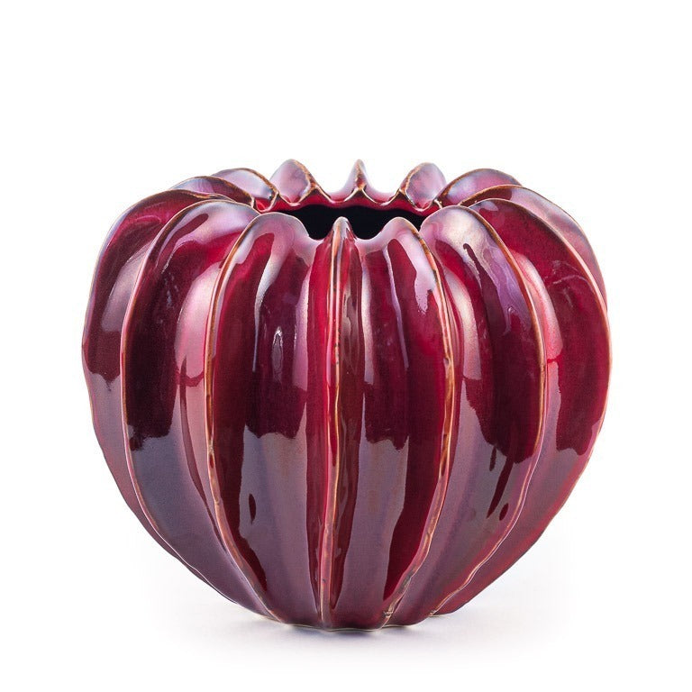 Die Des Pots | Vase bordeaux skulpturale Form (H 20 Ø 24,5 cm) von Des Pots zeichnet sich durch ein glänzendes, tiefrotes Rippendesign mit einer kürbisähnlichen Form und einer kleinen zentralen Öffnung aus, die einen eleganten Akzent vor einem weißen Hintergrund setzt.