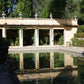 Ein rechteckiger Gartenpool spiegelt einen gelben Steinpavillon wider. Am 16.3.2027 | 14.30 – 15.30 Uhr AFTERNOON TEA Gartenreise durch Frankreich, mit offenen Türen und Steinverzierungen entlang der Dachlinie.