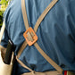 Eine Person, die ein blaues Hemd und eine hellbraune Niwaki | Schürze „Split Apron“ (94 × 63 cm) trägt, ist von hinten zu sehen. Die Schürze verfügt über gekreuzte Träger mit einem Lederaufnäher in der Mitte, was für Niwakis hohen Qualitätsanspruch steht. In die Tasche der Schürze ist ein schwarzer Gegenstand gesteckt.