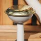 Eine Nahaufnahme des Auslaufs der „Plint | Gießkanne Medium 9 l in Weiß“ von PLINT A/S, mit einer runden, goldfarbenen, perforierten Rosette vor einem Holzhintergrund – perfekt für eine effektive Pflanzenbewässerung.