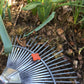 Ein Metallblattrechen, der in einem Gartenbeet neben grünen Trieben liegt, vorgestellt im Workshop der Königlichen Gartenakademie Di., 9.3.2027 | 10.00 – 12.00 Uhr WORKSHOP Frühlingsfit: Wie bereite ich den Garten auf die neue Saison vor?.