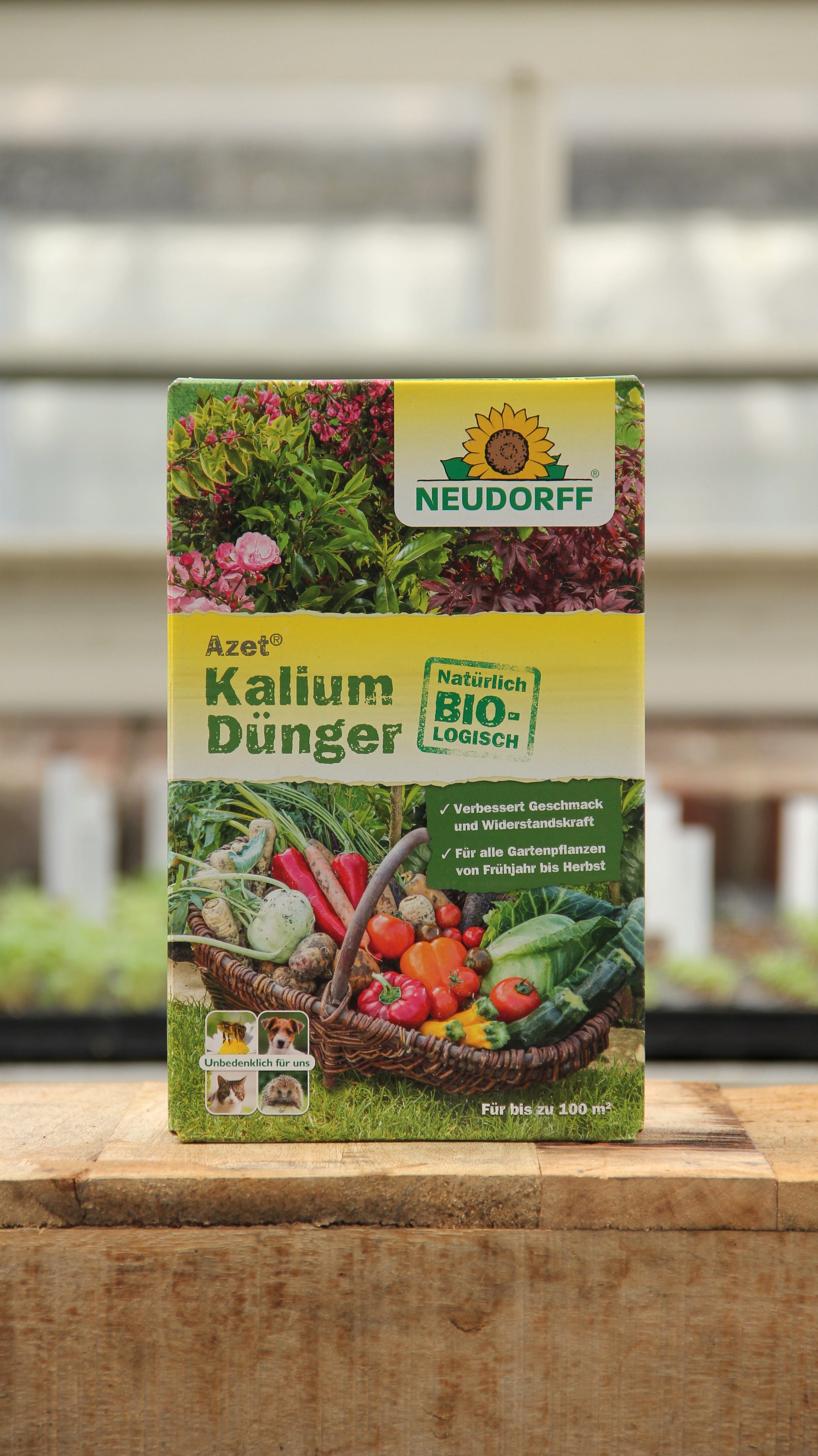Eine 2 kg Kiste Neudorff Azet Kalium Dünger steht auf Holz und zeigt Gemüse und Blumen auf seinem natürlichen, biologischen Etikett. Geeignet für frostbeständige Pflanzen und ideal als Kaliumdünger für Obst und Gemüse.
