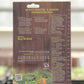 Rückseite der La'Bio Düngestäbchen 40 Stk. Packung von La'Bio, mit deutscher Anleitung, Dosierungstabelle, Strichcode und Abbildungen von Tomaten und Kräutern für gesundes Wachstum. Der Hintergrund zeigt unscharfe Zimmerpflanzen und ein Fenster.