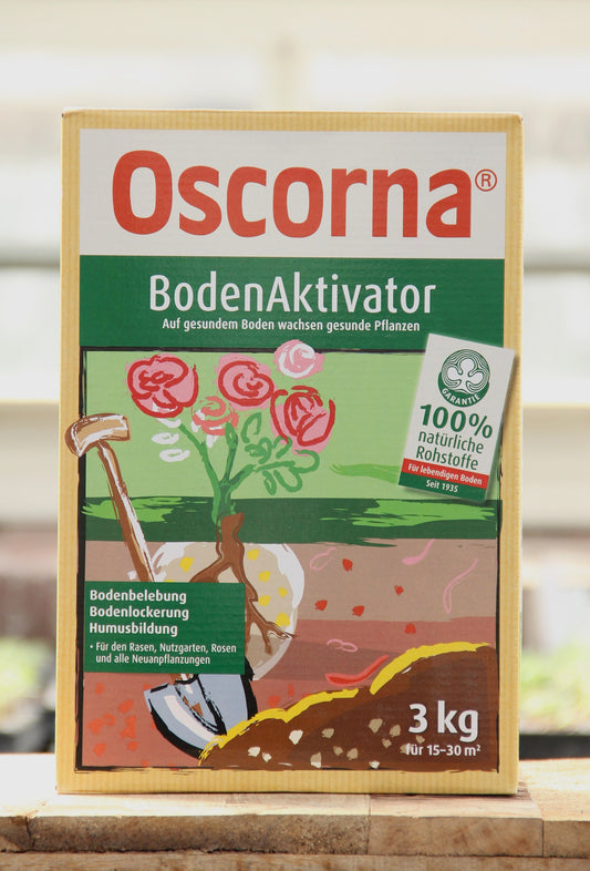 Oscorna | Boden Aktivator 3 kg ist ein Bodenaktivator für gesundes Pflanzenwachstum. Die Schachtel mit einer Schaufel und Blumen hebt 100 % natürliche Materialien hervor - ideal für Rasen, Rosen, Neupflanzungen und zur Verbesserung des pH-Werts im Boden.