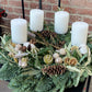 Nehmen Sie an dem "Sa. 21.11.2026 | 10.00 - 12.00 WORKSHOP Adventskranzbinden bis zu 30 cm" der Königlichen Gartenakademie und gestalten Sie einen festlichen Kranz mit weißen Kerzen, Tannenzapfen, getrockneten Zitrusfrüchten, Zimtstangen und Grünzeug auf einem stilvollen schwarzen Ständer.