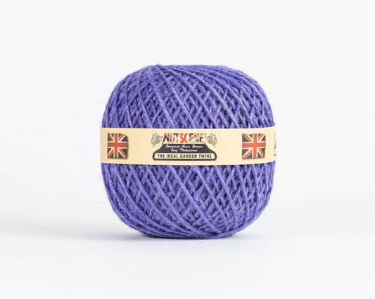 Ein Knäuel Nutscene | Heritage Jutegarn in der Farbe Flieder, 130 m, von Nutscene Twines Ltd ist zu einer ordentlichen Kugel gewickelt. Es ist mit einem beigen Etikett versehen, das mit britischen Flaggen und dem Schriftzug „Nutscene – The Ideal Garden Twine“ auf weißem Hintergrund verziert ist.