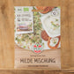 Packung von Sperli's | Bio Keimsprossen Saatgut 'Milde Mischung' mit Bildern von frischen Sprossen und Gerichten auf der Vorderseite. Mit Bio-Keimsprossen-Zertifizierung, deutschem Text und Holzuntergrund. Marke: Sperli's.