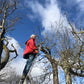 Ein älterer Mann in roter Jacke demonstriert unter blauem Himmel beim Zwei-Tages-Masterkurs Obstbaumschnitt für Profis der Königlichen Gartenakademie am 15.01. und 16.01.2026 fachmännische Schnitttechniken im Freien.