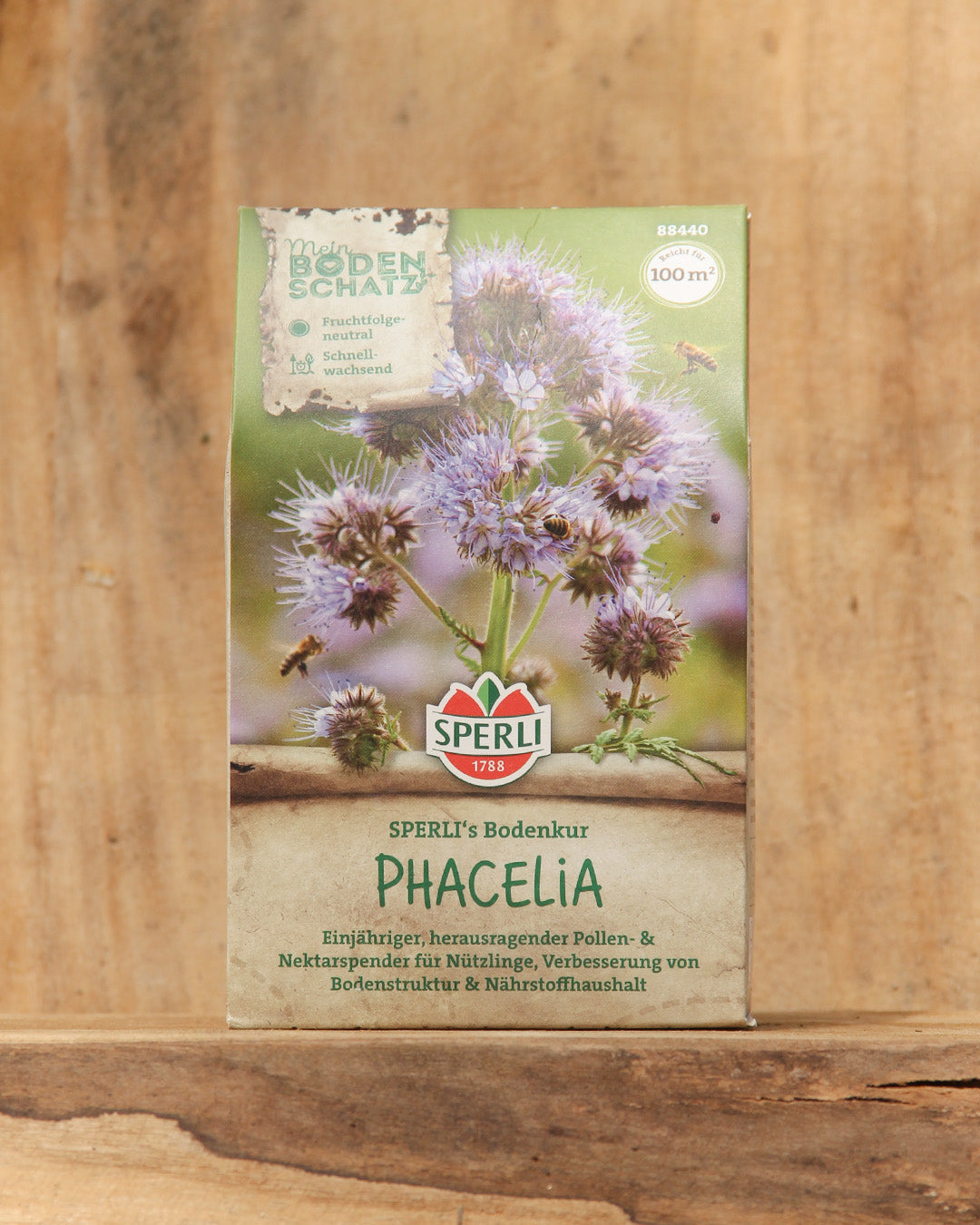 Eine 350g-Packung von Sperli's | Bodenkur 'Phacelia' BIO-Samen zeigt blühende Phacelia-Blüten mit violetten Blütenblättern auf einem Holzhintergrund. Die Verpackung weist auf die Verwendung als Gründünger zur Bodenverbesserung hin.