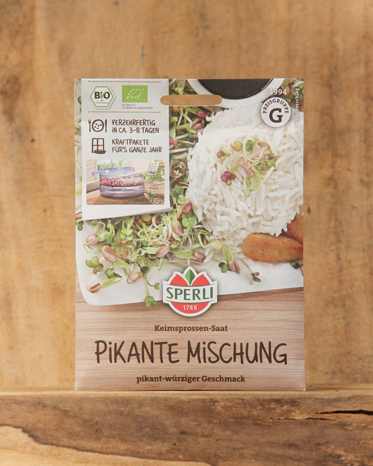 Eine Packung Bio Keimsprossen Saatgut 'Pikante Mischung' von Sperli liegt auf einer Holzfläche aus. Auf der Packung sind Keimsprossen mit Reis und Gemüse abgebildet, zusammen mit Bio- und Qualitätssiegeln.
