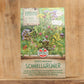 Eine Packung Sperli's | Bodenkur 'Schnellgrüner' 450 g steht aufrecht auf einer Holzunterlage mit bunten Wildblumen-Illustrationen und deutschem Text über diesen schnell wirkenden Bodenverbesserer von Sperli's.