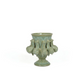 Die Vase Des Pots | Vase mit Schneckenmotiv aus Steingut H 18 Ø 18 ist eine grünliche Steingutvase mit ausgestelltem Rand und umlaufenden Schneckenmotiven, die auf einem kurzen Sockel steht.