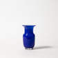 Eine Des Pots | Blaue Vase aus Glas in Kelchform (H 18 cm, Ø 11 cm) wird mit einem weit ausladenden Rand vor einem schlichten weißen Hintergrund präsentiert, der einen weichen Schatten nach rechts wirft. Marke: Des Pots.