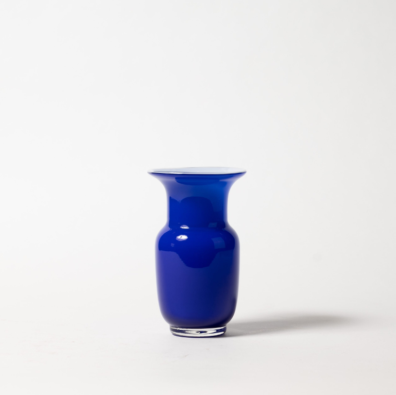 Eine Des Pots | Blaue Vase aus Glas in Kelchform (H 18 cm, Ø 11 cm) wird mit einem weit ausladenden Rand vor einem schlichten weißen Hintergrund präsentiert, der einen weichen Schatten nach rechts wirft. Marke: Des Pots.