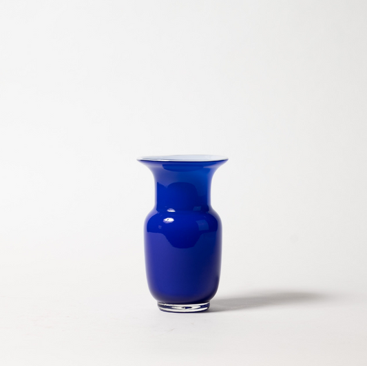 Eine Des Pots | Blaue Vase aus Glas in Kelchform (H 18 cm, Ø 11 cm) wird mit einem weit ausladenden Rand vor einem schlichten weißen Hintergrund präsentiert, der einen weichen Schatten nach rechts wirft. Marke: Des Pots.