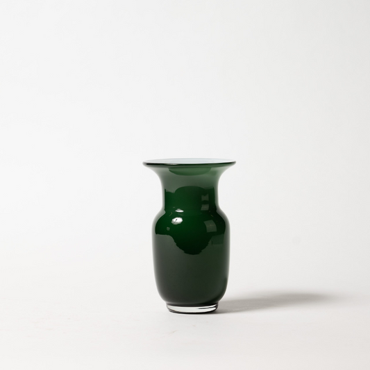 Die Des Pots | Grün Vase aus Glas in Kelchform (H 18 cm, Ø 11 cm) von Des Pots hat einen glänzend dunkelgrünen, breit ausgestellten Rand und einen abgerundeten Körper. Sie steht auf einem schlichten weißen Hintergrund, der einen weichen Schatten nach rechts wirft.